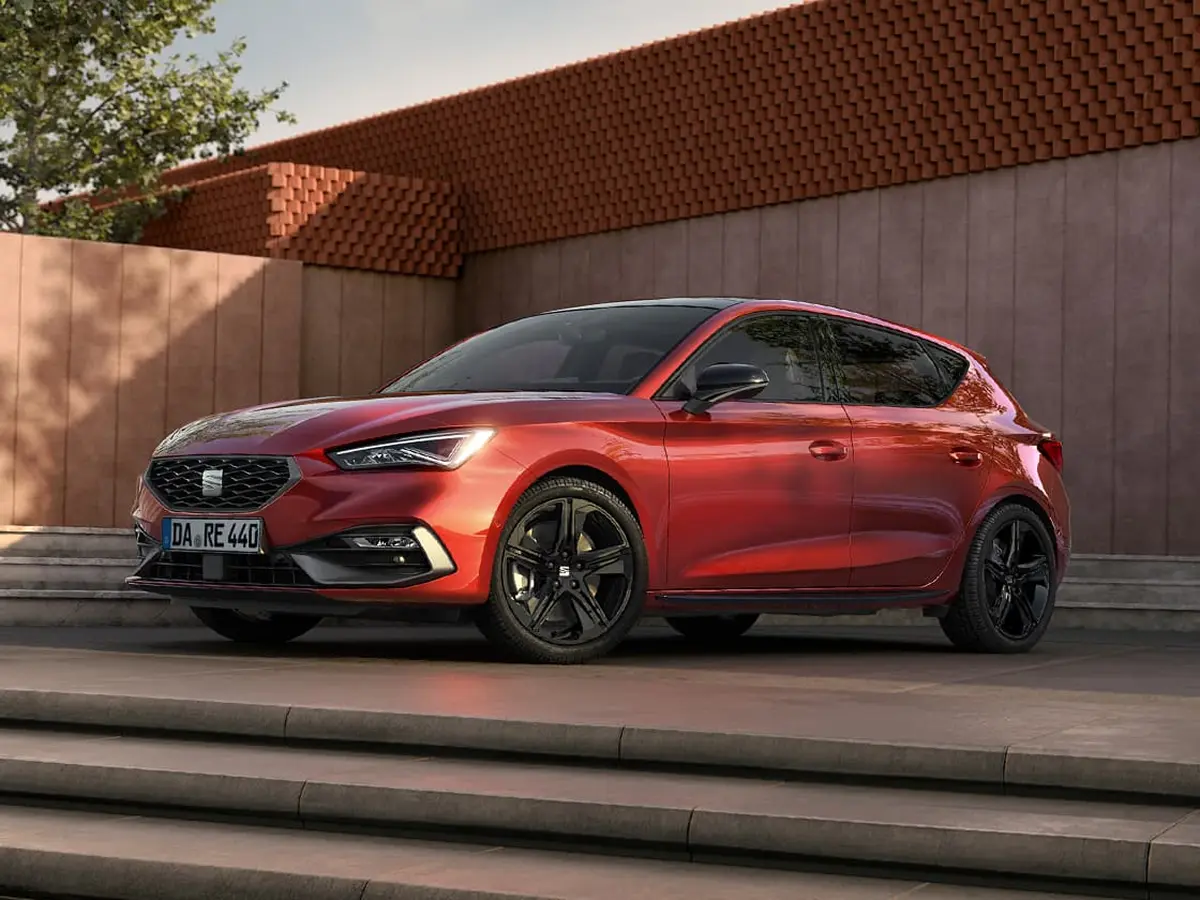 SEAT Leon FR Black Edition in Rot seitlich von vorne fotografiert, geparkt auf Stufen vor moderner Fassade