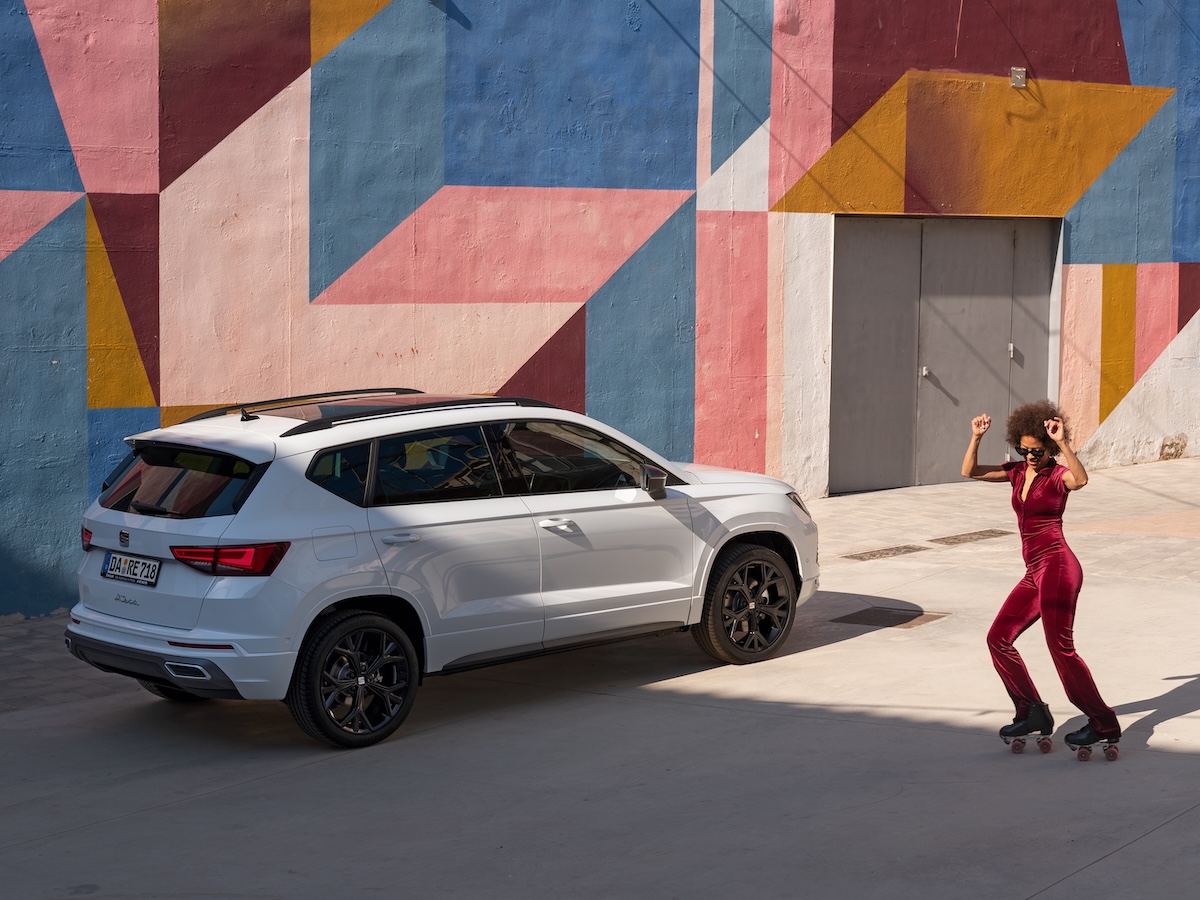 SEAT Ateca in Weiß geparkt vor einer farbenfrohen Wand, im Vordergrund eine Person auf Rollschuhen.